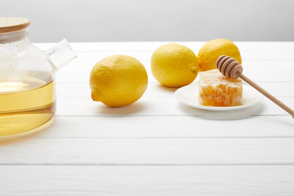 bule transparente com chá verde, limões e favo de mel na mesa de madeira branca
 - Foto, Imagem