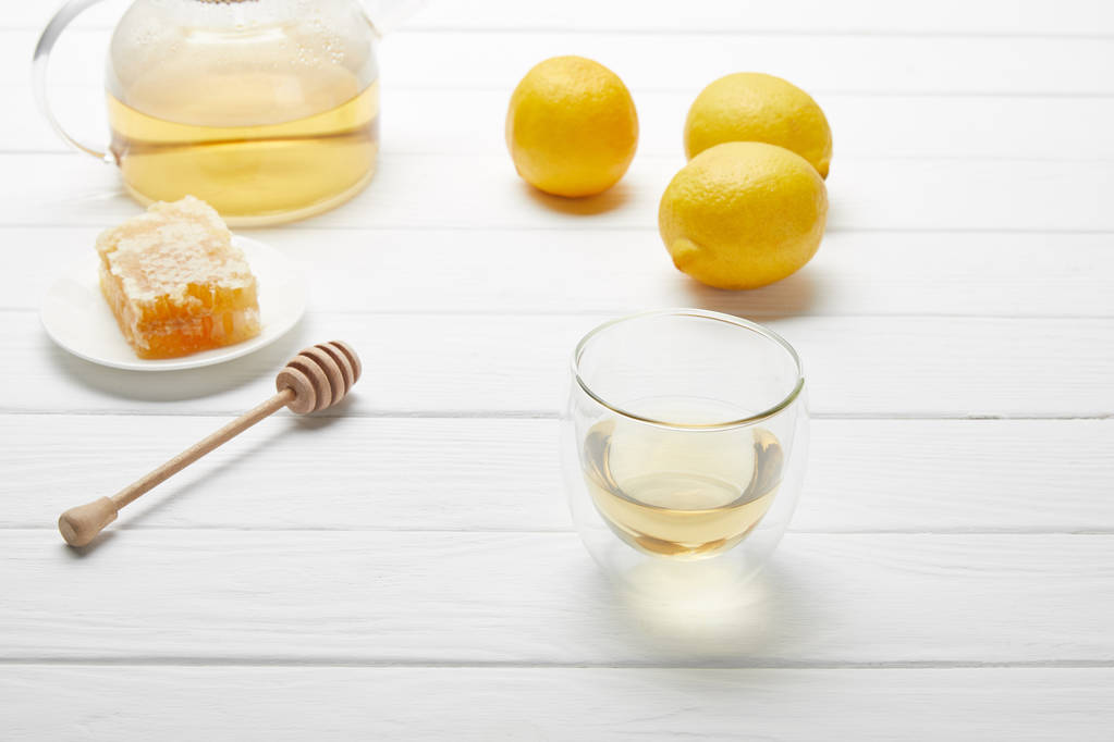 透明なティーポットとグラス緑茶、レモン、蜂蜜ドリッパー、ハニカムを白い木製のテーブルに - 写真・画像