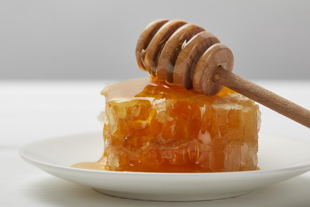 enfoque selectivo de la placa con delicioso panal y gotero de miel aislado en gris
 - Foto, Imagen