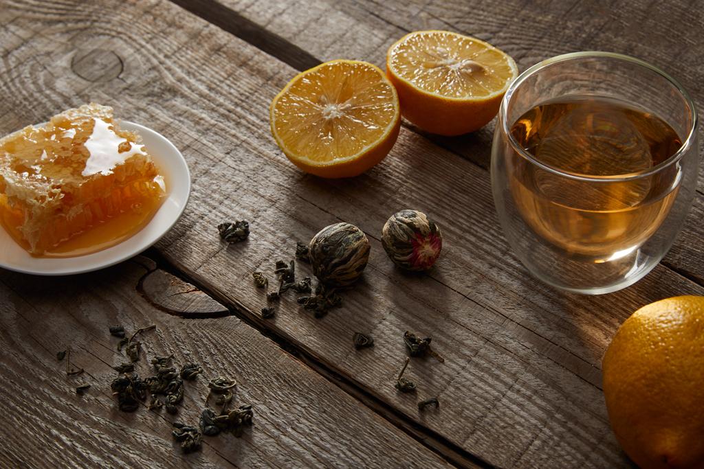 glass of chinese blooming tea, lemons and honeycomb on wooden table  - Photo, Image