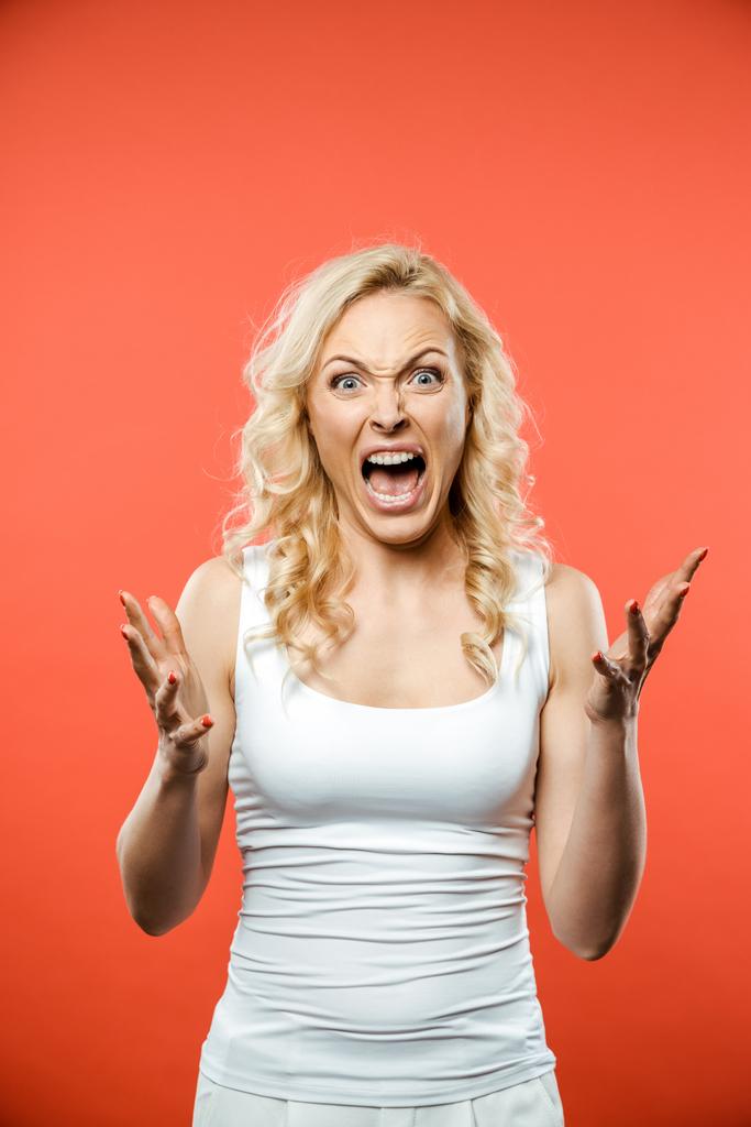 scared blonde woman looking at camera and screaming on red  - Photo, Image