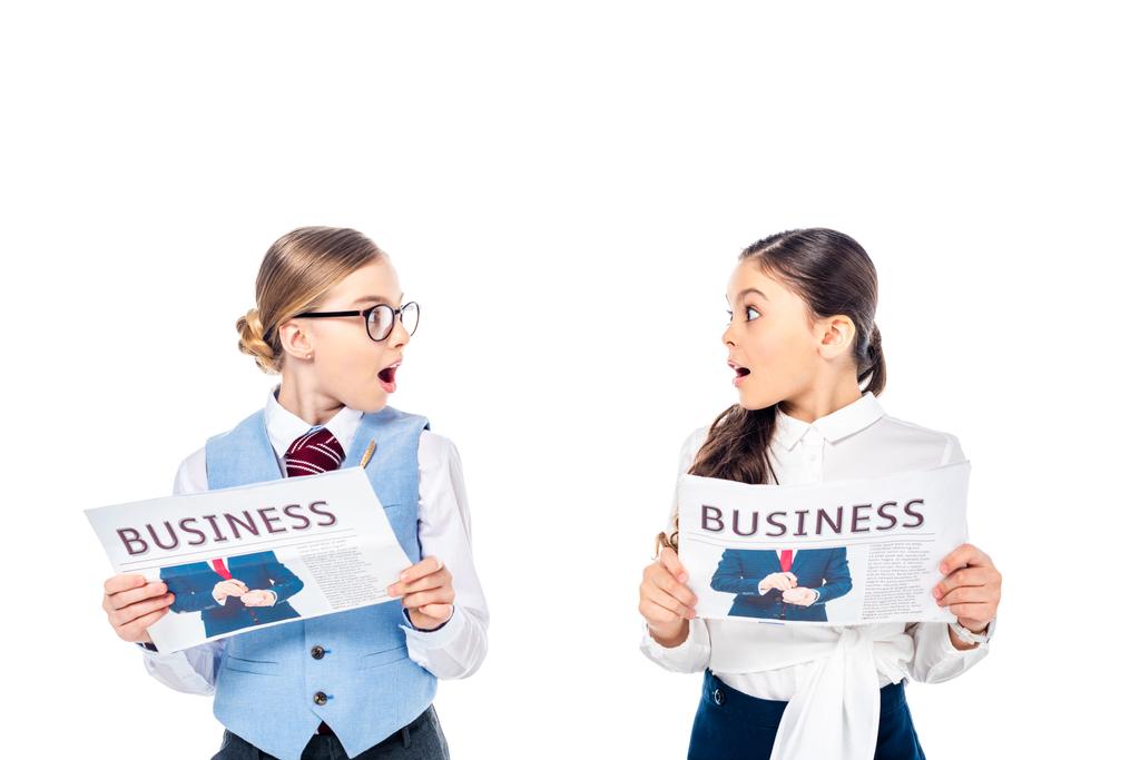 здивовані школярки в офіційному вбранні з бізнес-газетами, дивлячись один на одного Ізольовані на білому
 - Фото, зображення