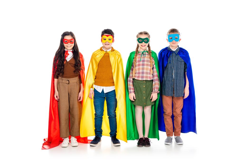 szczęśliwe dzieci w SuperHero kostiumy i maski patrząc na kamerę na białym - Zdjęcie, obraz