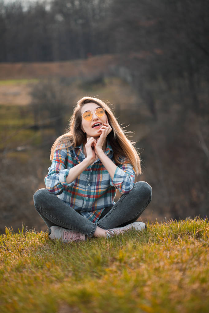 Veselá mladá žena, která sedí na kopci. - Fotografie, Obrázek