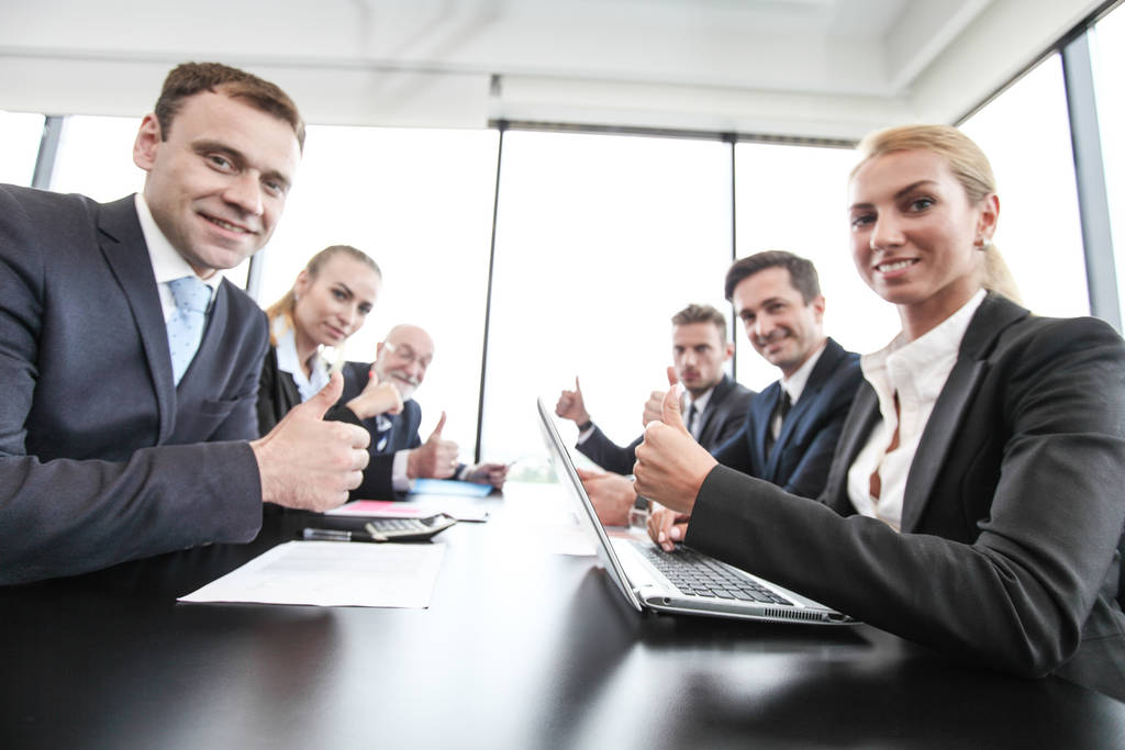 Grupo mixto de personas en reuniones de negocios que trabajan con documentos y computadoras que muestran pulgares hacia arriba
 - Foto, imagen