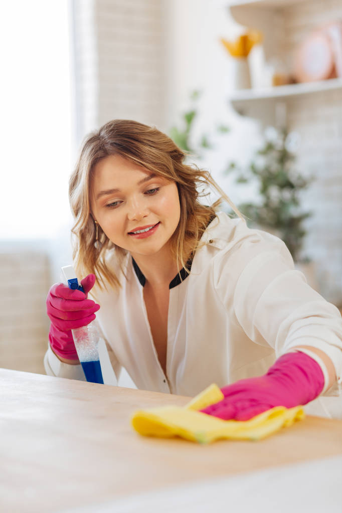 Ευχάριστη νεαρή γυναίκα καθαρίζοντας μια επιφάνεια πάγκο - Φωτογραφία, εικόνα