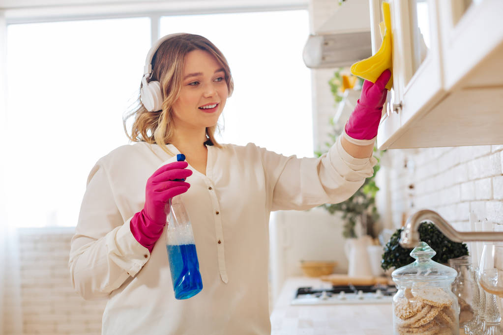 Веселая милая молодая женщина убирает свою кухню
 - Фото, изображение