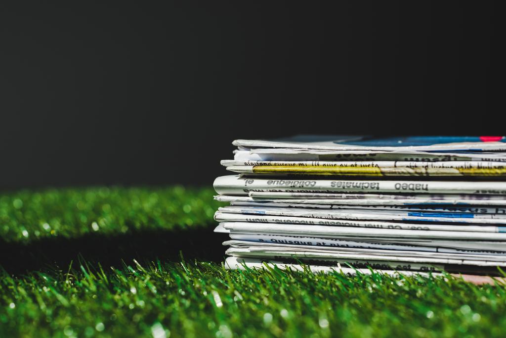 pile de journaux imprimés différents sur herbe verte fraîche isolé sur noir
 - Photo, image
