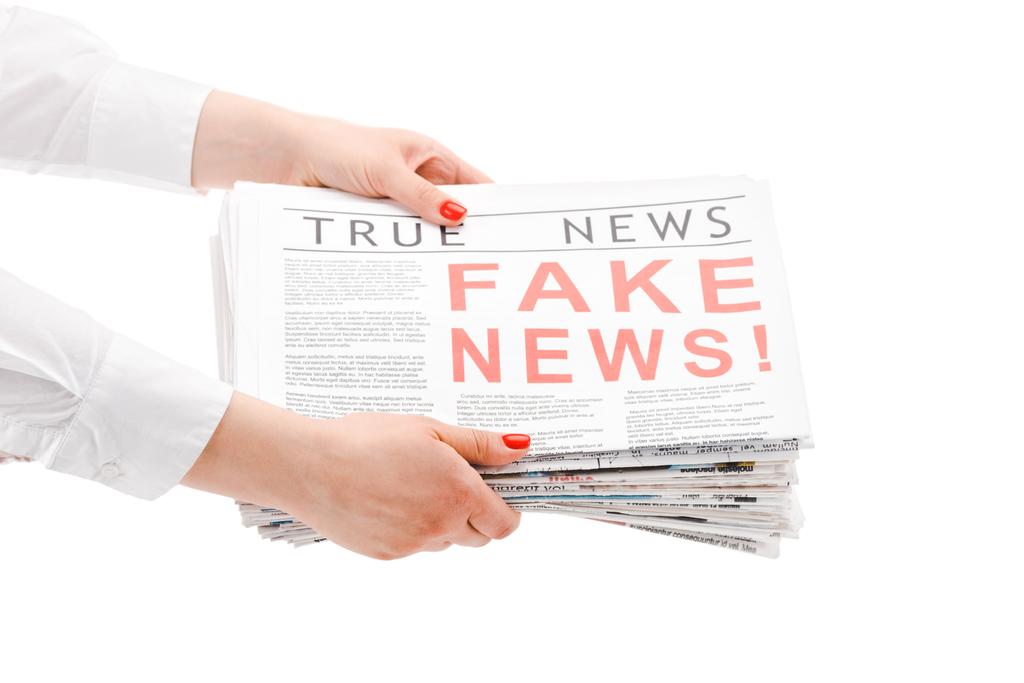 обрезанный вид женщины, держащей кучу газет с фальшивыми и истинными новостями изолированы на белом
 - Фото, изображение