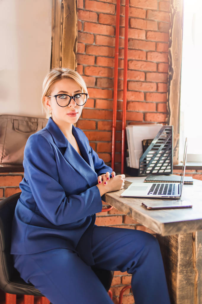 Красивая умная деловая женщина сидит за столом на рабочем месте с ноутбуком
 - Фото, изображение