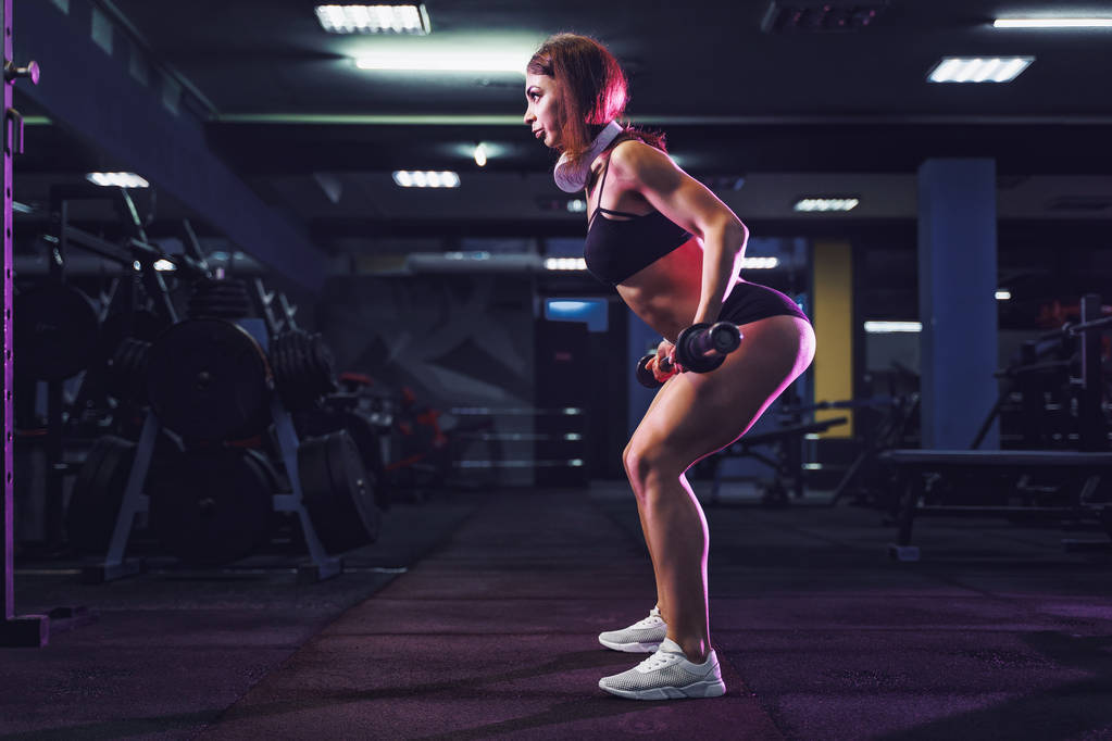 Attractive fit sexy woman in the gym crouches with a barbell. Woman training back - Photo, Image