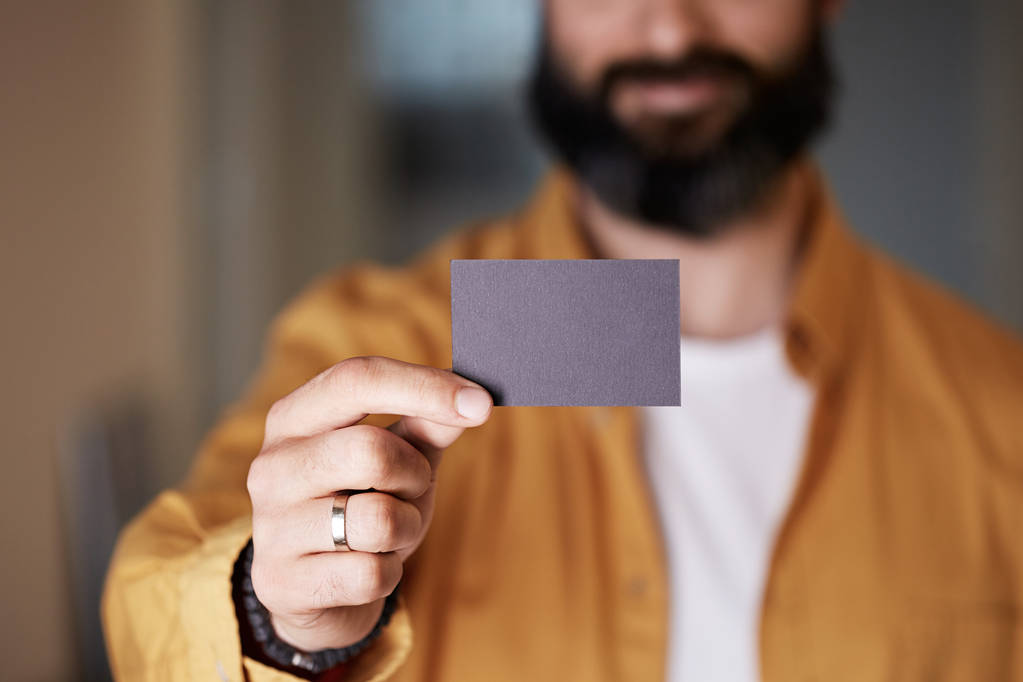 Бородатый предприниматель дает руку пустой черной визитной карточки на размытом фоне. Макет Copy Paste Blank Реклама
. - Фото, изображение