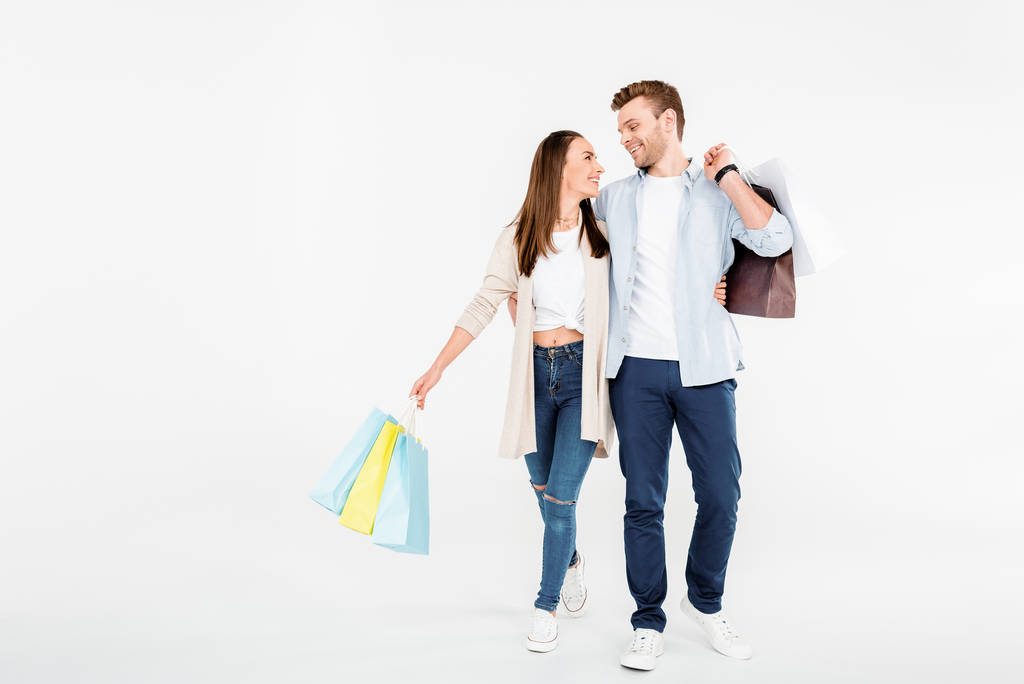 幸せな若いカップルが買い物袋を抱いて、互いを見て - 写真・画像