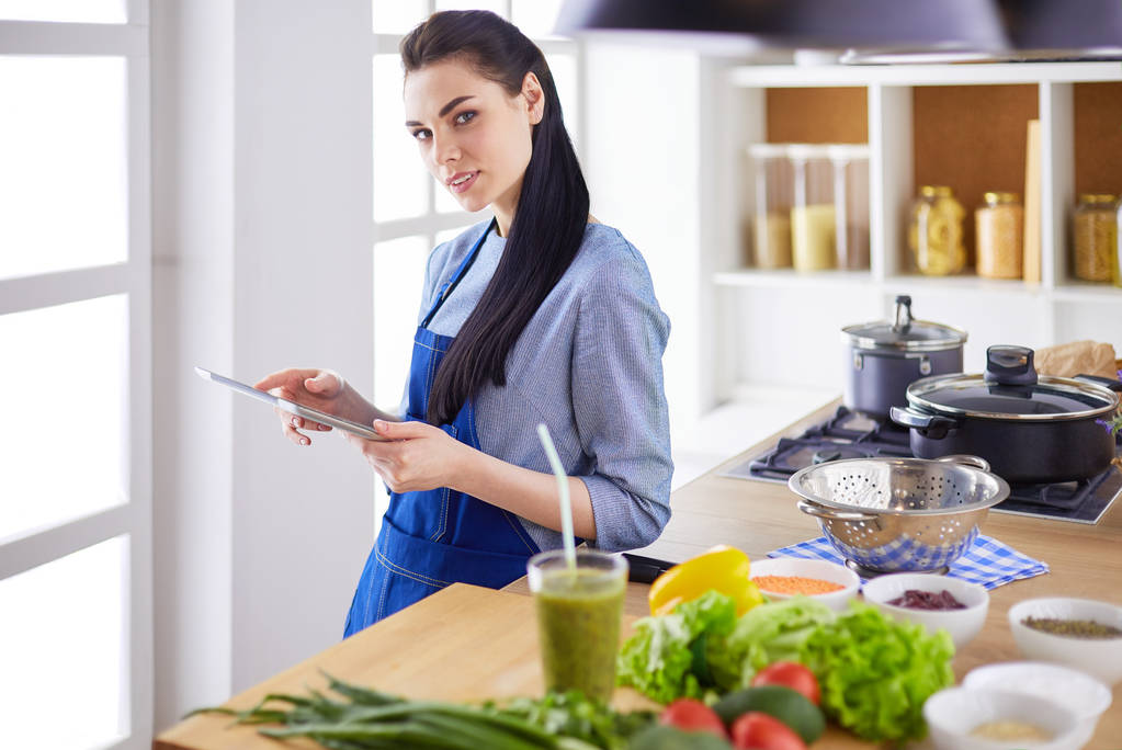 Junge Frau kocht mit Tablet-Computer in ihrer Küche - Foto, Bild