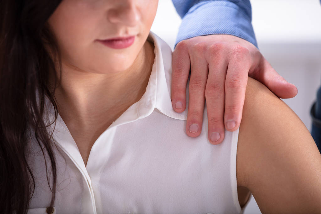 Бизнесмен трогает плечо молодой женщины-коллеги на рабочем месте
 - Фото, изображение