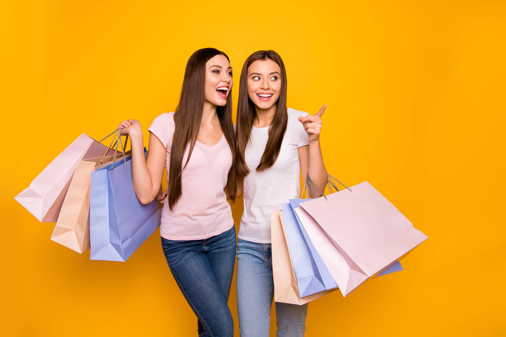 Portrait of nice cute charming feminine attractive cheerful straight-haired girls embracing holding in hands carrying new cool purchase isolated on bright vivid shine yellow background - Photo, Image