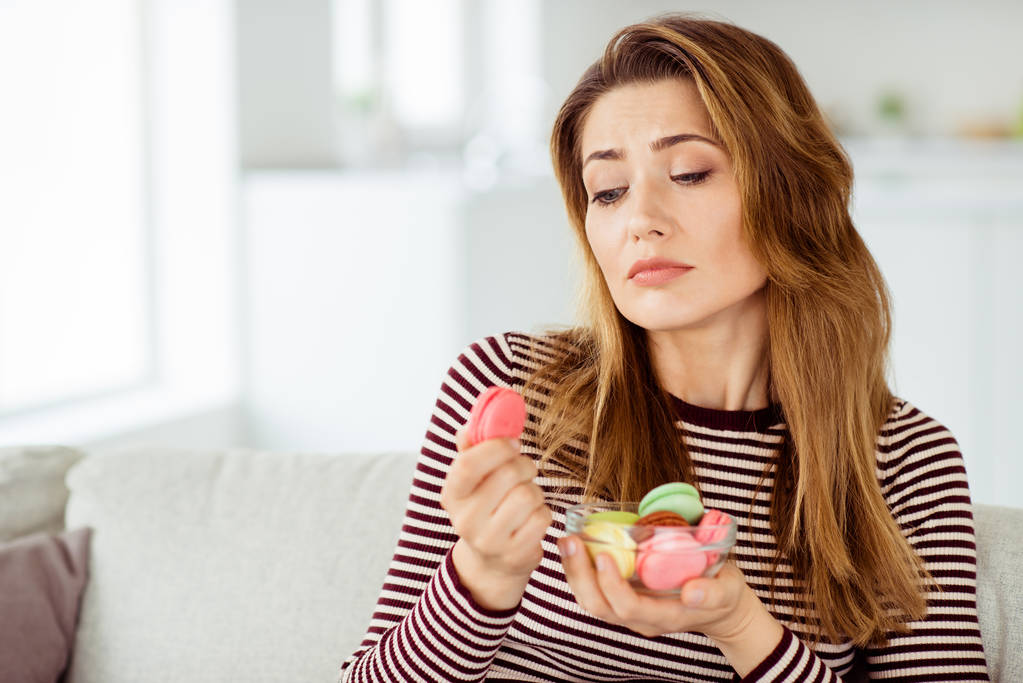 Close-up portrait of her she nice cute charming lovely lonely attractive wavy-haired girlfriend alone eating colorful cookies pile stack break-up with boyfriend in light white interior room - Photo, Image