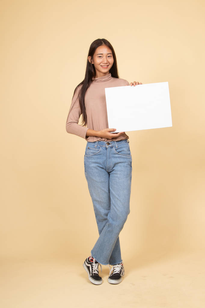 Cuerpo completo de mujer asiática joven con blanco signo en blanco
. - Foto, imagen