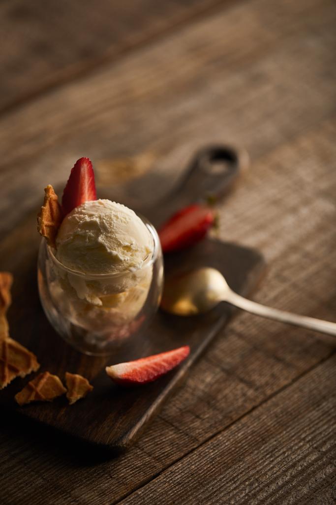 selektivní zaměření lahodné zmrzliny s jahodami ve skle a lžičkách na dřevěném stole - Fotografie, Obrázek