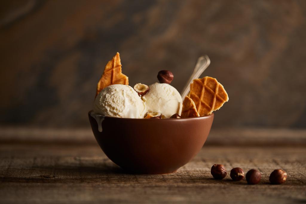 maukkaita jäätelökauhoja vohvelin ja hasselpähkinöiden paloilla kulhossa puupöydällä
 - Valokuva, kuva