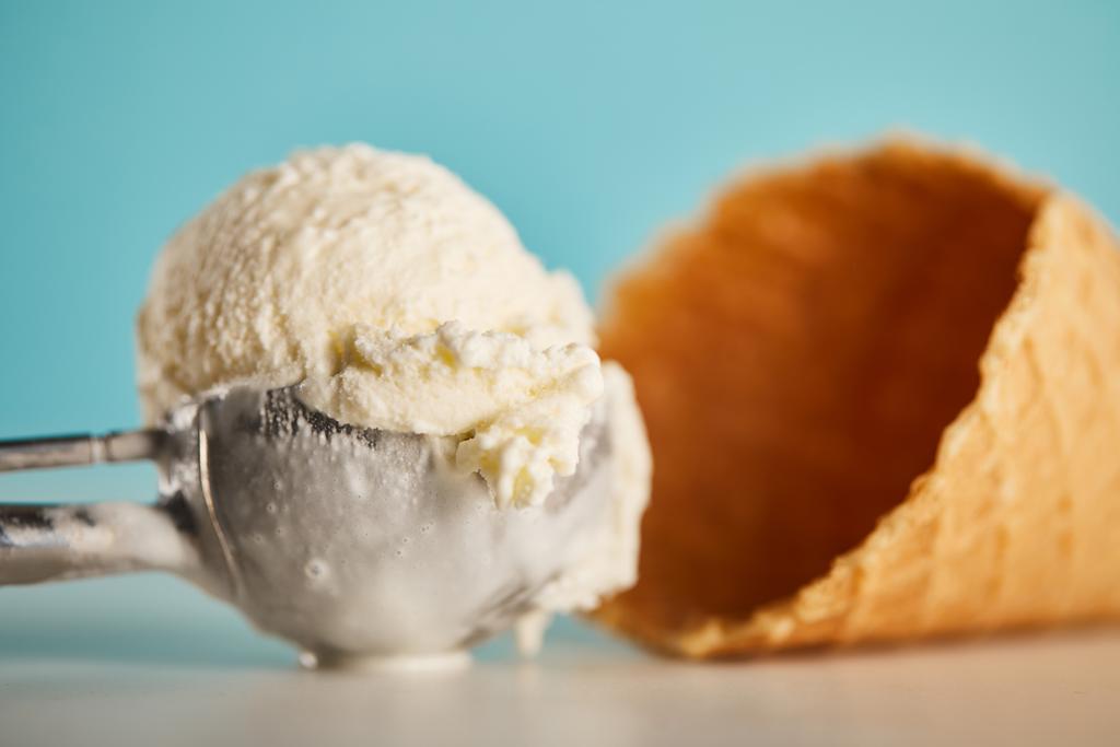 νόστιμο παγωτό σέσουλα σε κουτάλι και βάφλα κώνο στο μπλε - Φωτογραφία, εικόνα