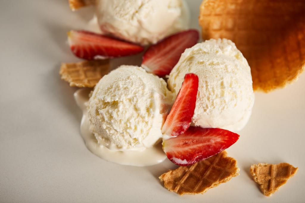 Nahsicht auf Waffelstücke und köstliches schmelzendes Eis mit Erdbeeren auf grau - Foto, Bild