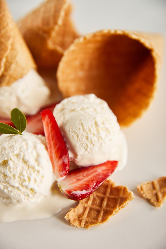 закрытый вид на вафельные рожки и вкусное тающее мороженое с клубникой на сером
 - Фото, изображение