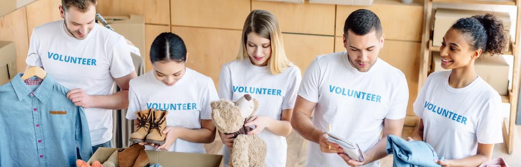 plano panorámico de jóvenes voluntarios multiculturales trabajando juntos en el centro de caridad
 - Foto, imagen