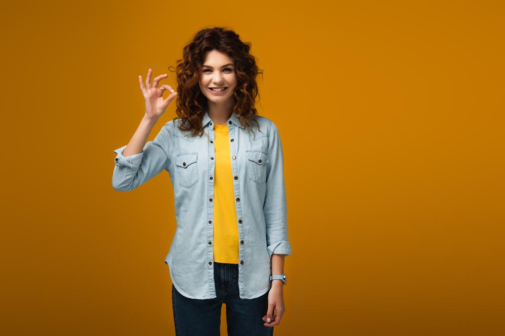 alegre rizado pelirroja mujer de pie y mostrando ok signo en naranja
  - Foto, imagen