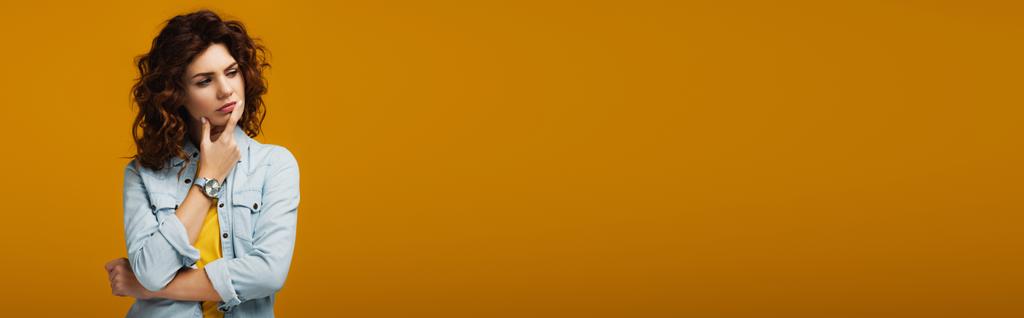 plano panorámico de mujer pelirroja pensativa pensando mientras está de pie en naranja
  - Foto, Imagen