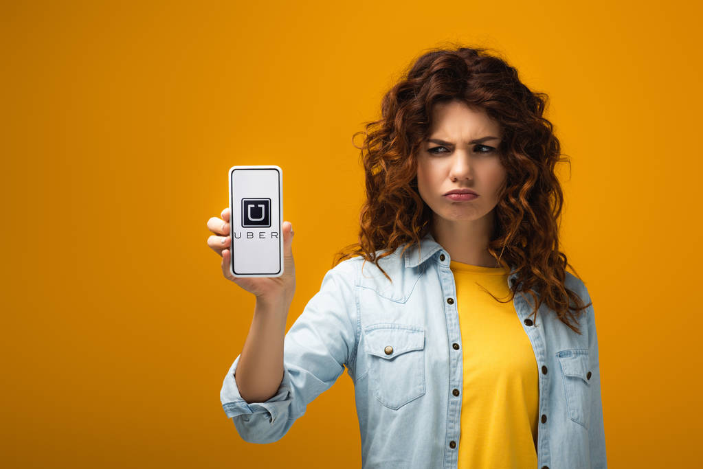 turuncu ekranda uber uygulaması ile akıllı telefon tutan üzgün redhead kadın  - Fotoğraf, Görsel