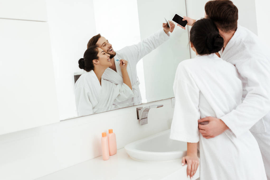 iloinen mies halaus onnellinen nainen kylpytakissa ottaen selfie kylpyhuoneessa
  - Valokuva, kuva