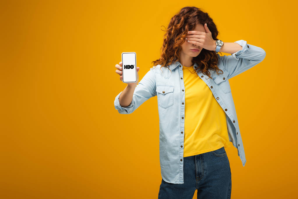 redhead kadın gözleri kaplayan ve turuncu ekranda hbo uygulaması ile akıllı telefon tutarak  - Fotoğraf, Görsel