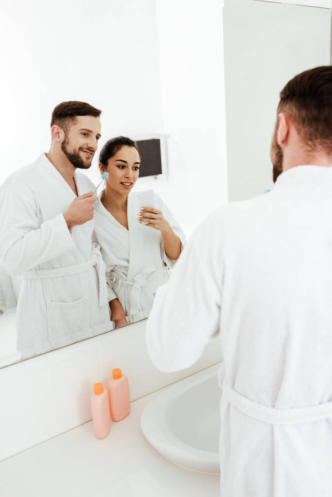 foyer sélectif de femme brune gaie prendre des photos avec l'homme heureux tenant brosse à dents
  - Photo, image