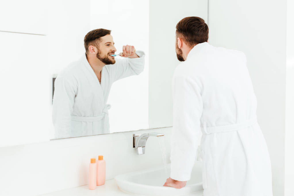 selektivní zaměření hezkého vousatého muže, jak čistit zuby v koupelně  - Fotografie, Obrázek