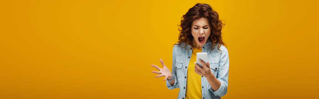 plan panoramique de rousse en colère femme gesticulant tout en regardant smartphone et criant sur orange
  - Photo, image