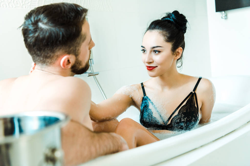 Selektiver Fokus glücklicher Mädchen, die bärtige Männer in der Badewanne betrachten  - Foto, Bild