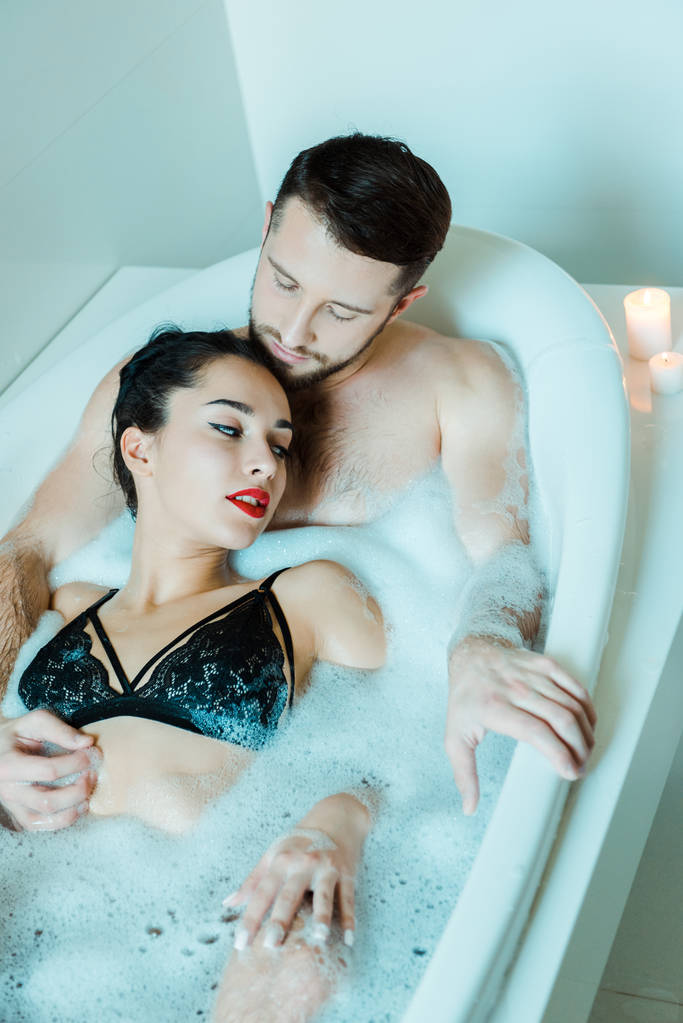 вид зверху привабливої брюнетки дівчина лежить з бородатим чоловіком у ванній
  - Фото, зображення