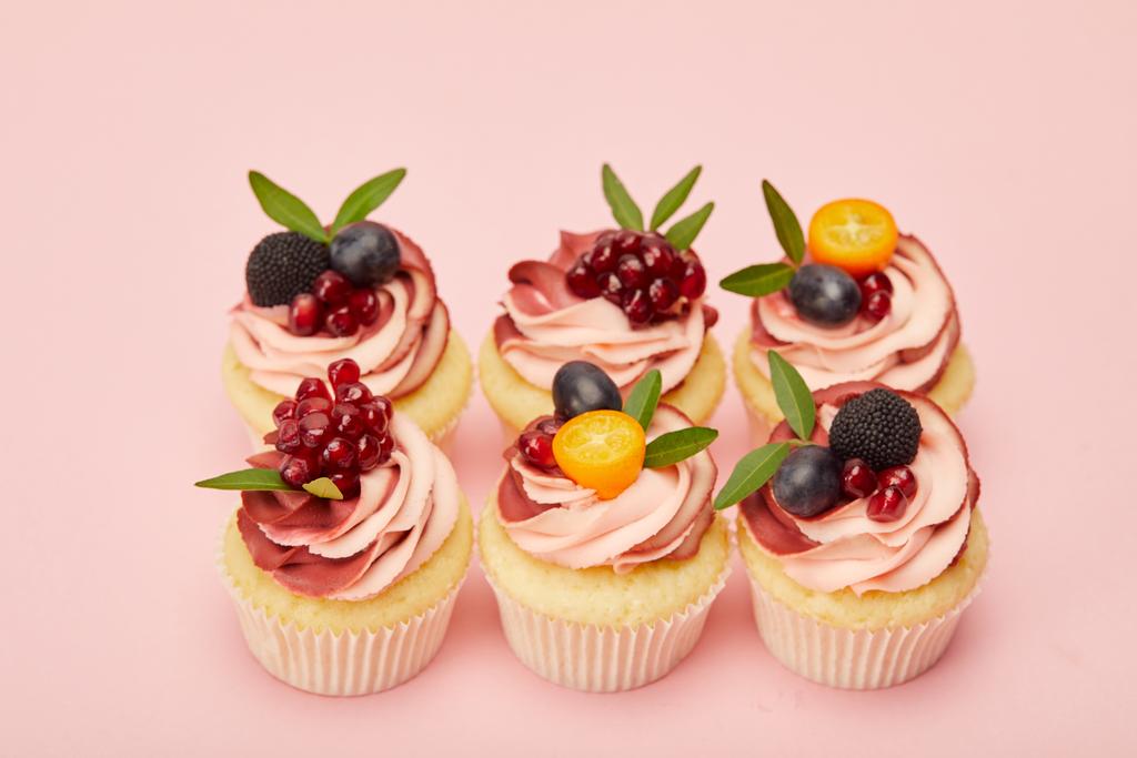 zoete Cupcakes met fruit en bessen op roze oppervlak - Foto, afbeelding