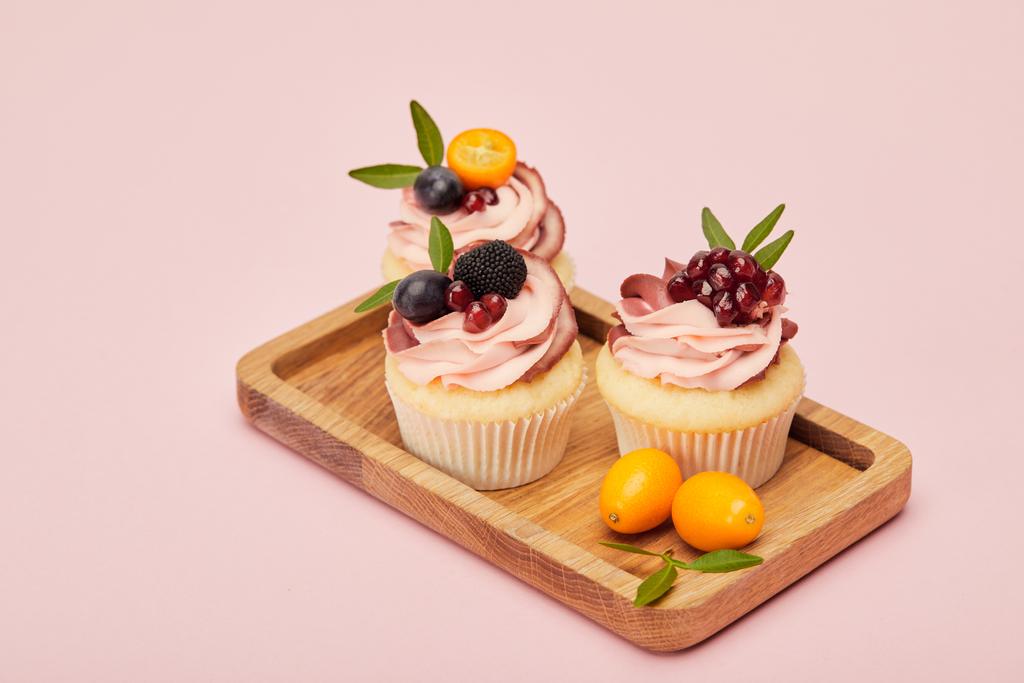 zoete Cupcakes met bessen en vruchten geïsoleerd op roze - Foto, afbeelding