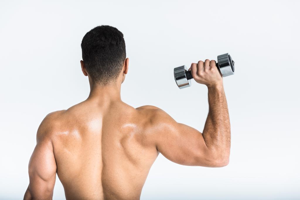 Rückenansicht des sportlichen Mannes mit muskulösem Oberkörper, der eine Hantel auf weiß hält - Foto, Bild