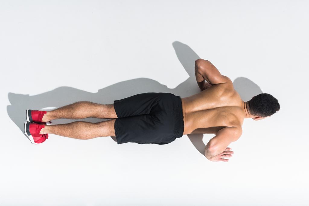vista aérea del hombre deportivo sin camisa haciendo flexiones en blanco
 - Foto, Imagen