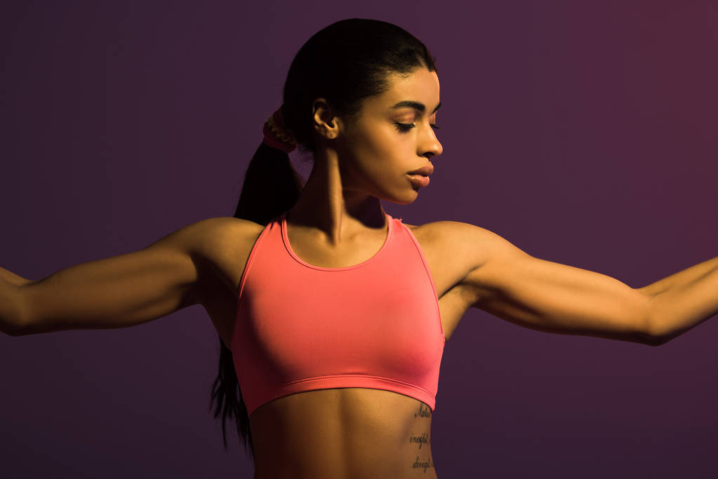 bastante atlética chica afroamericana en rosa sujetador deportivo aislado en púrpura
 - Foto, imagen