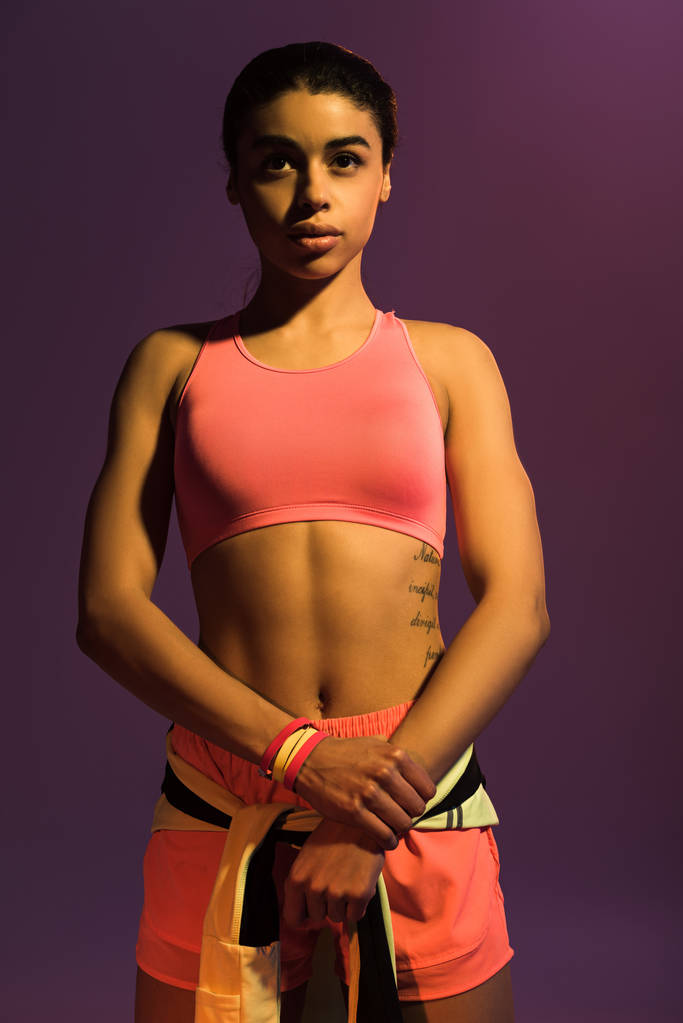 довольно спортивная африканская американская девушка в розовом спортивном бюстгальтере изолированы на фиолетовый
 - Фото, изображение