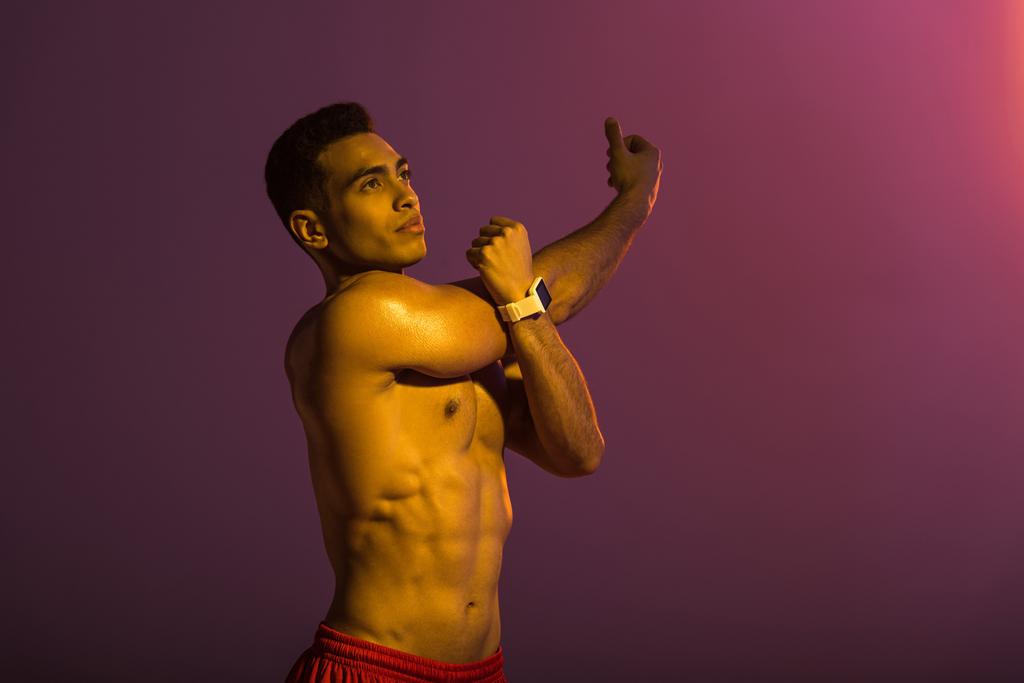 bel homme sportif dans la montre intelligente étirement sur fond violet
 - Photo, image