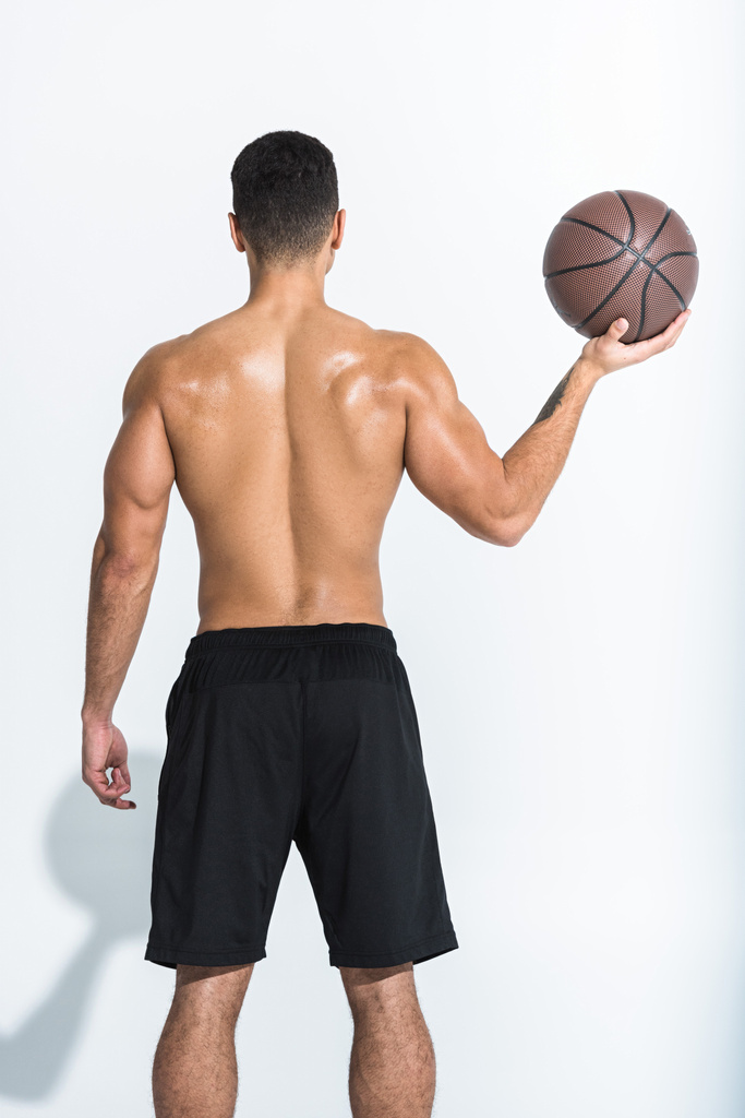 вид ззаду спортсмена в чорних шортах, що тримає коричневий м'яч на білому
 - Фото, зображення