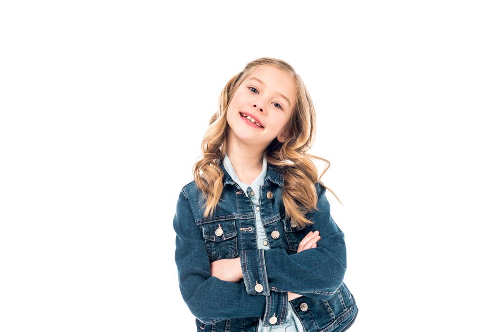 Kid in denim jasje staande met gekruiste armen en glimlachend geïsoleerd op wit - Foto, afbeelding