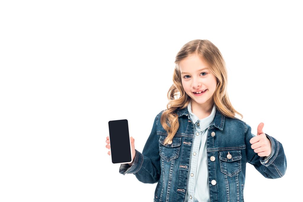 niño sonriente en chaqueta de mezclilla sosteniendo teléfono inteligente con pantalla en blanco y mostrando el pulgar hacia arriba aislado en blanco
 - Foto, Imagen