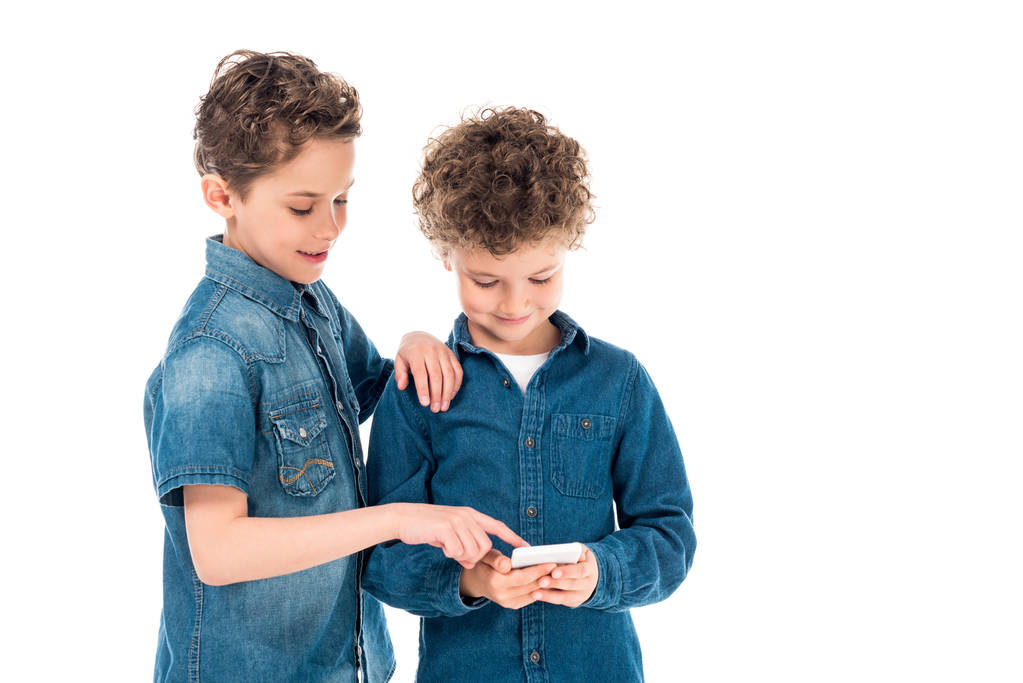 白で隔離されたスマートフォンを使用してデニムシャツの2人の子供 - 写真・画像