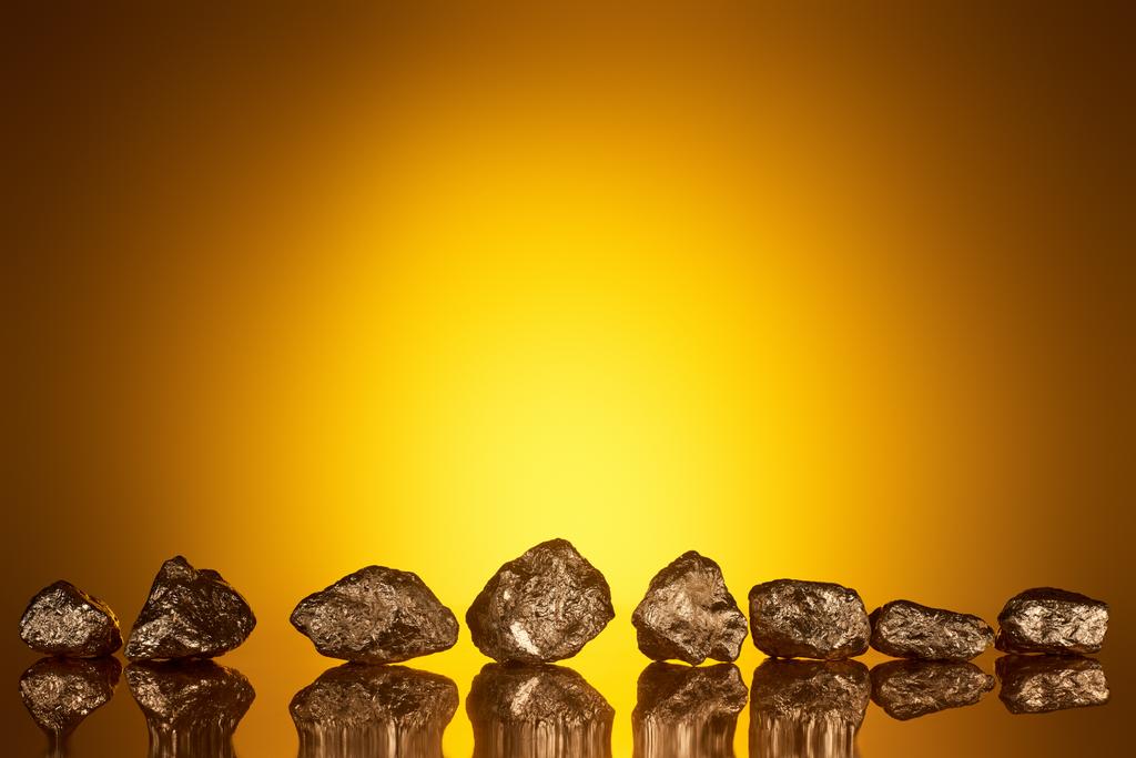 zlaté lesklé kameny s odrazem a žlutým zadním světlem  - Fotografie, Obrázek